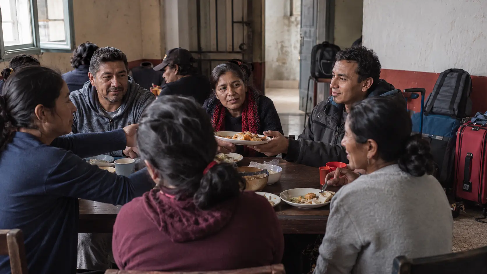 Un grupo de vecinos compartiendo la comida con migrantes